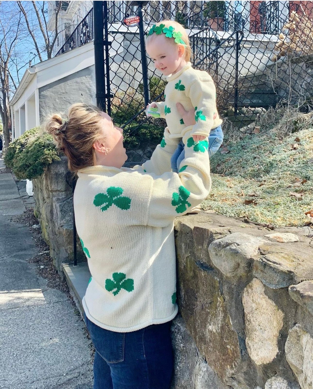 mom wearing sweater holding up daughter who is wearing the same sweater