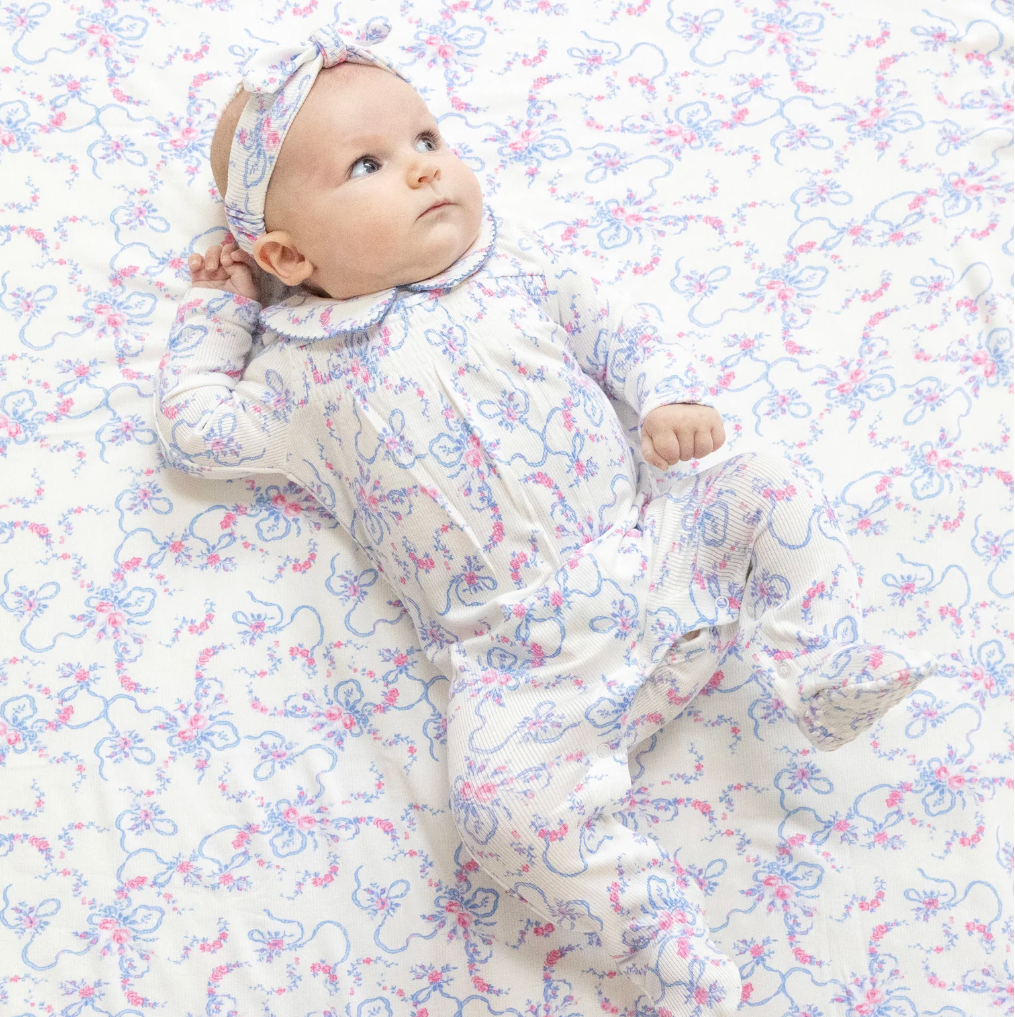 Baby in a floral outfit lying on a matching floral blanket