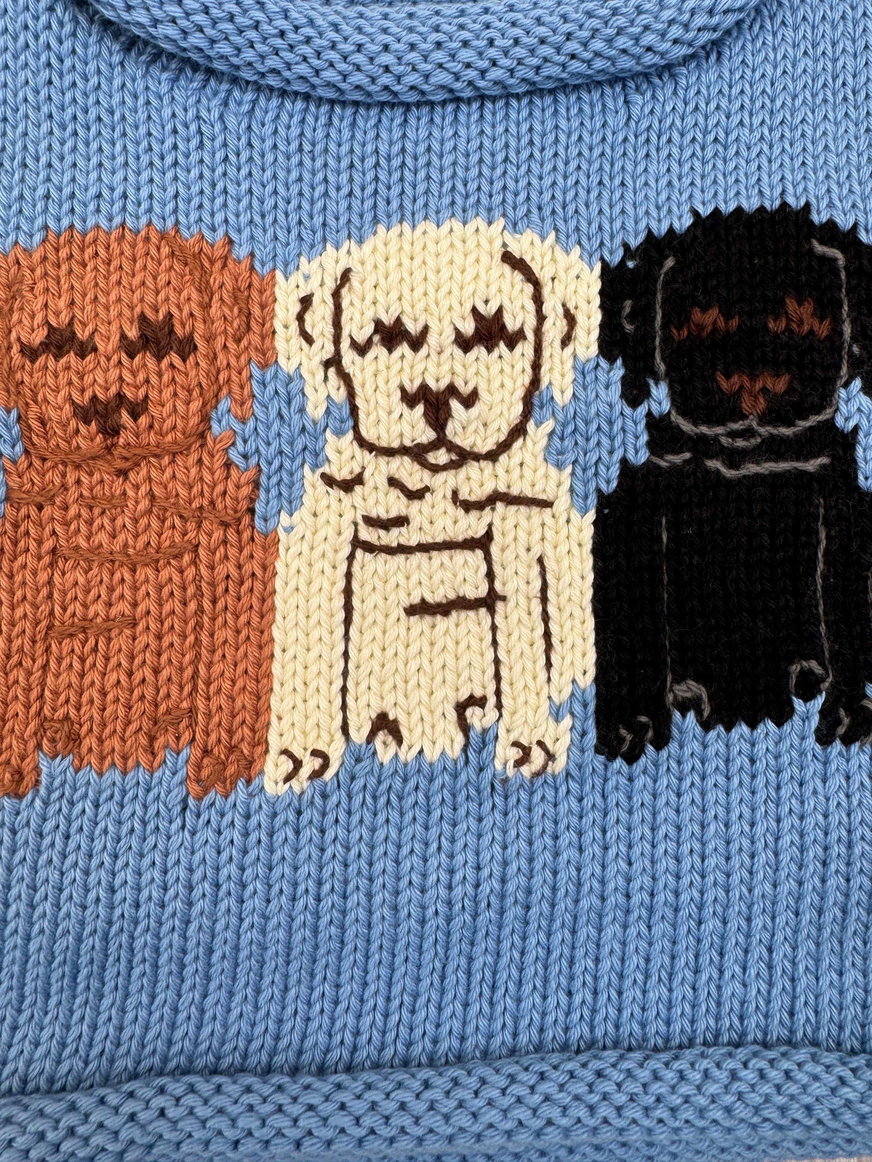 Knitted sweater with brown, white, and black dog illustrations on a blue background