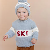 Child wearing a blue knitted sweater with &