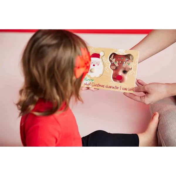 Child looking at a mirror with Christmas-themed character options held by an adult.
