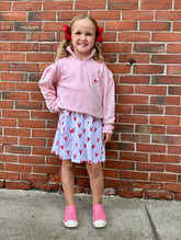 Young girl in pink outfit standing against a brick wall