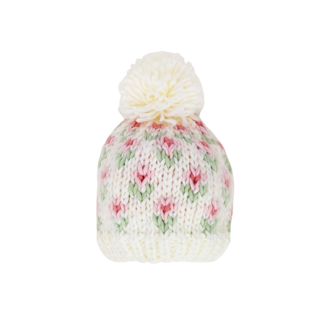 Knitted beanie with floral pattern and white pom-pom on a white background