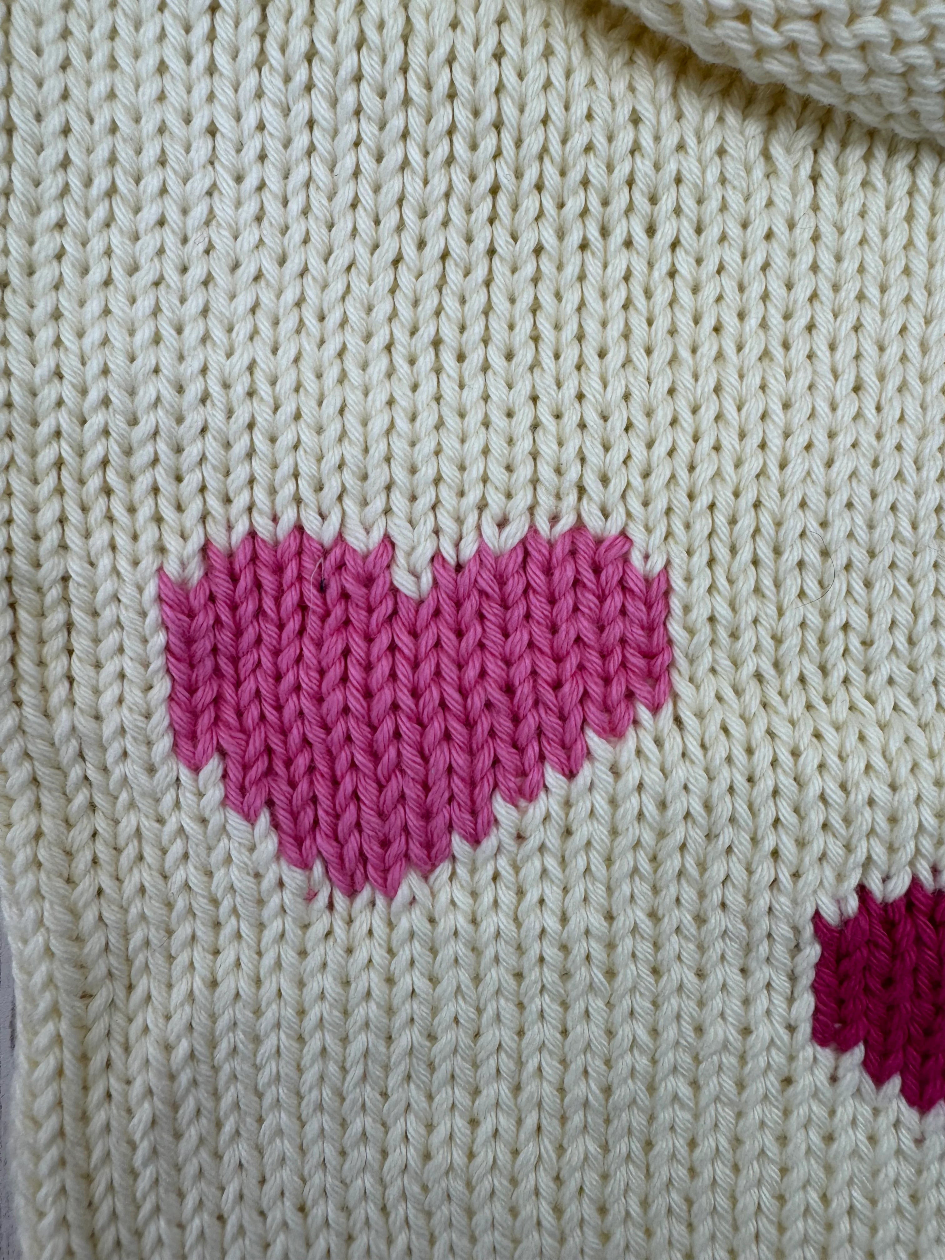 Close-up of a beige knitted fabric with pink floral patterns.