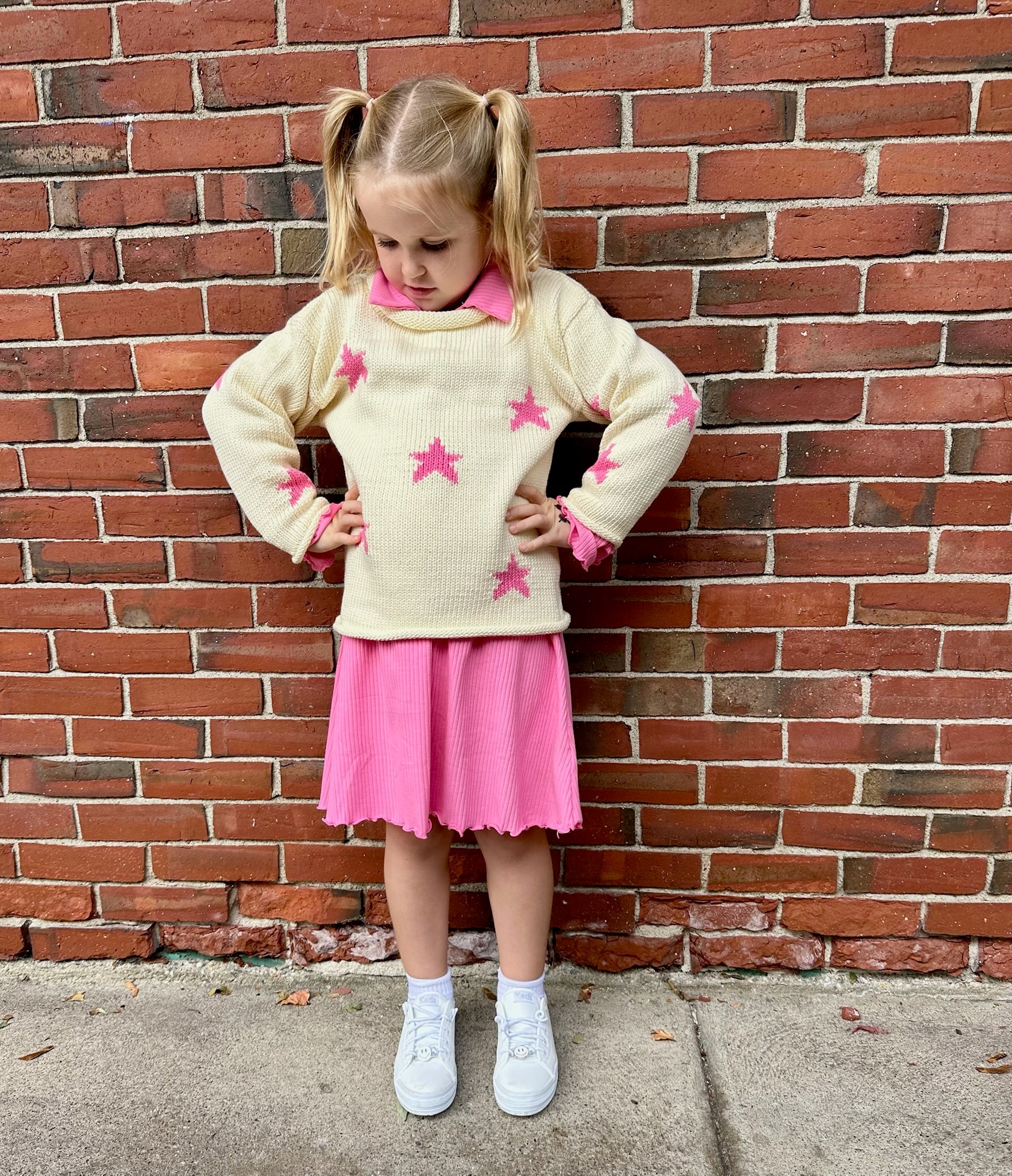 girl wearing pink dress under star sweater
