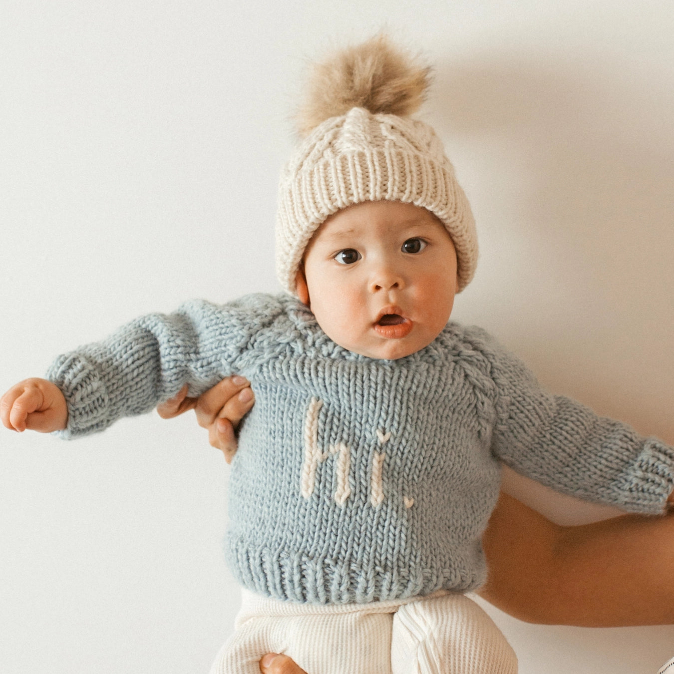 Baby wearing a blue knitted sweater with &