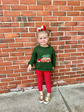 girl wearing green christmas sweater and red leggings