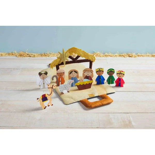 Felt nativity scene with characters and a manger on a wooden surface.