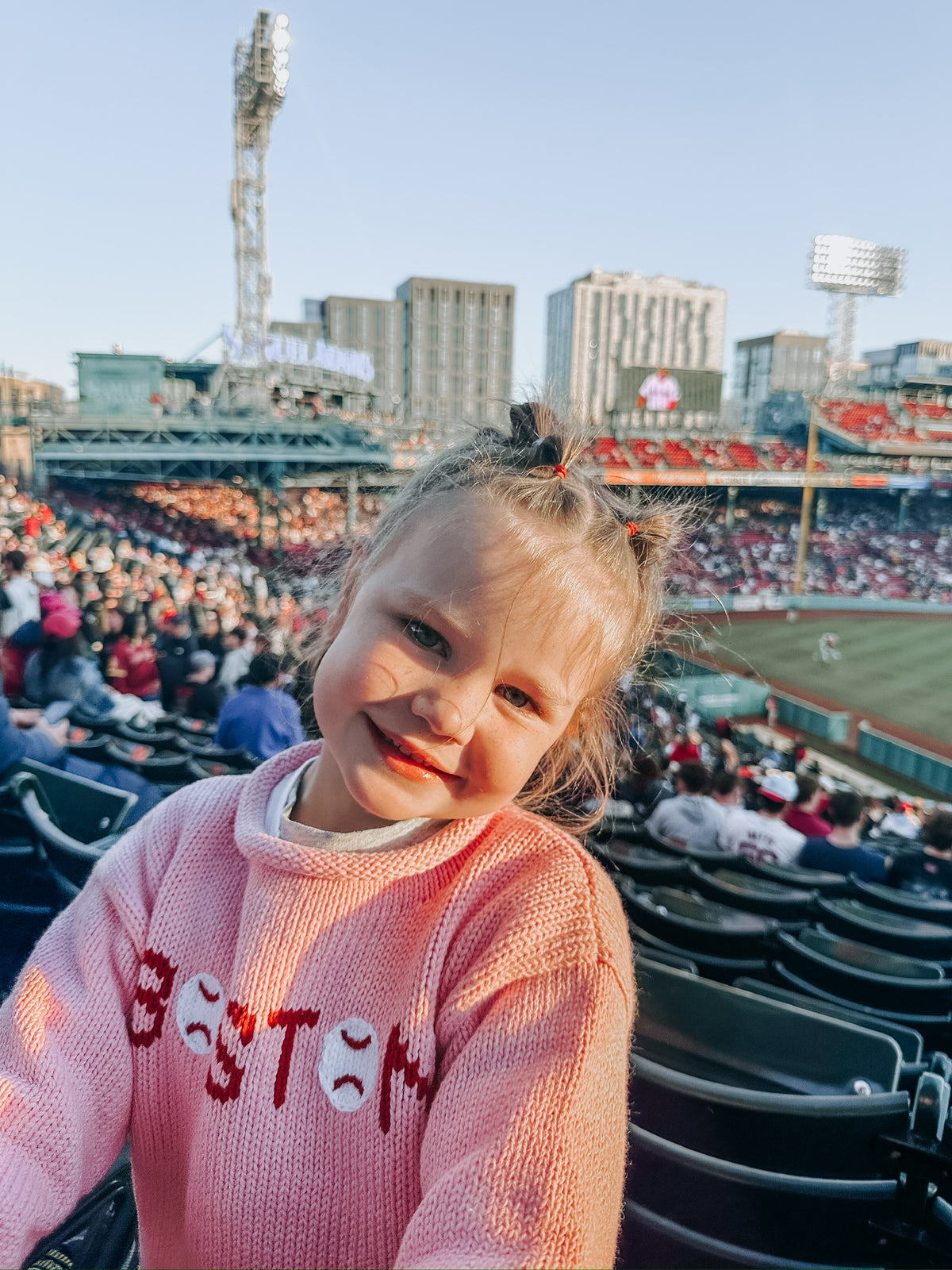 A young girl smiling in a pink knit sweater with &