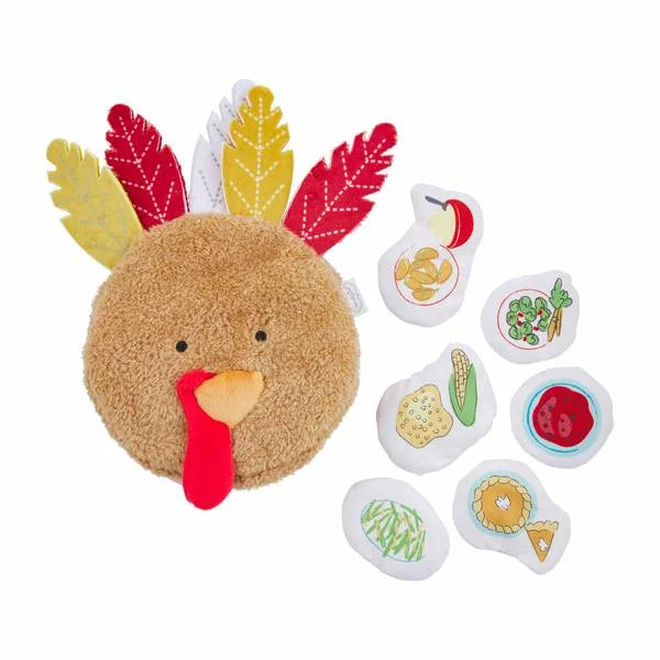 Plush toy shaped like a turkey with detachable food pieces on a white background