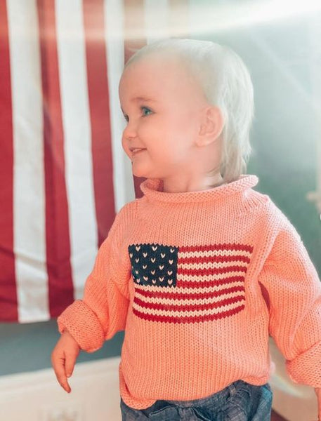 baby wearing sweater with American flag in background