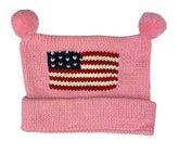 pink hat with bottom rolled up once and two pink poms at top and red white and blue american flag in center
