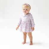 Young child wearing a floral dress on a white background