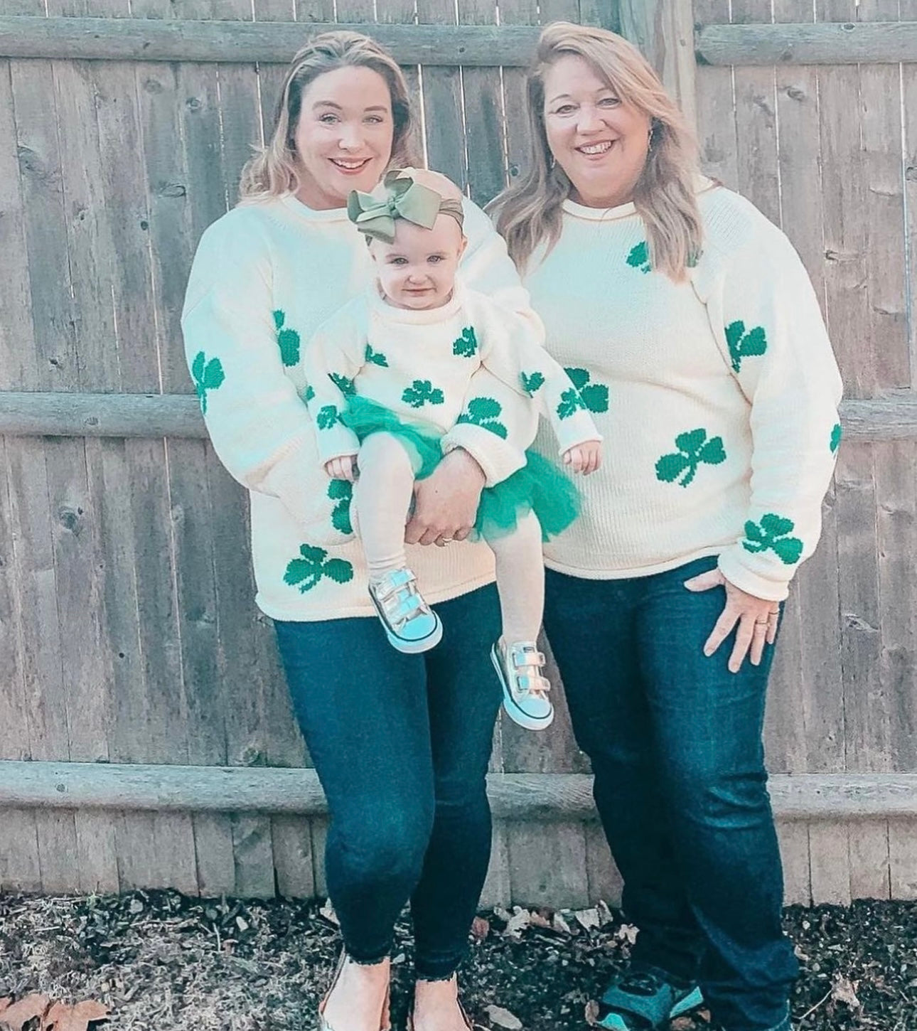 two women both wearing Ladies Ivory Shamrock Sweater, one holding baby girl who is also wearing the children&