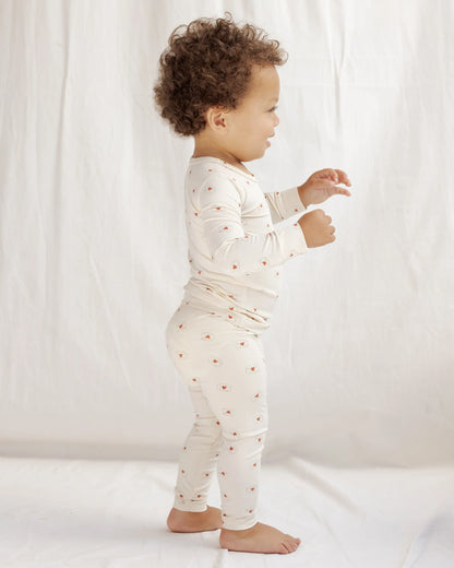 Child wearing a white outfit with small red patterns on a plain background