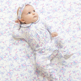 Baby in a floral outfit lying on a matching floral blanket