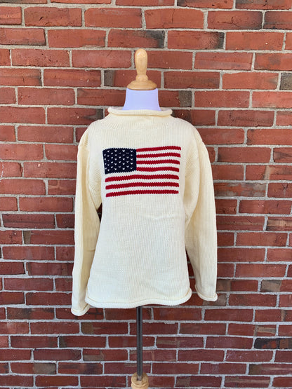 White sweater with American flag design on a brick wall background