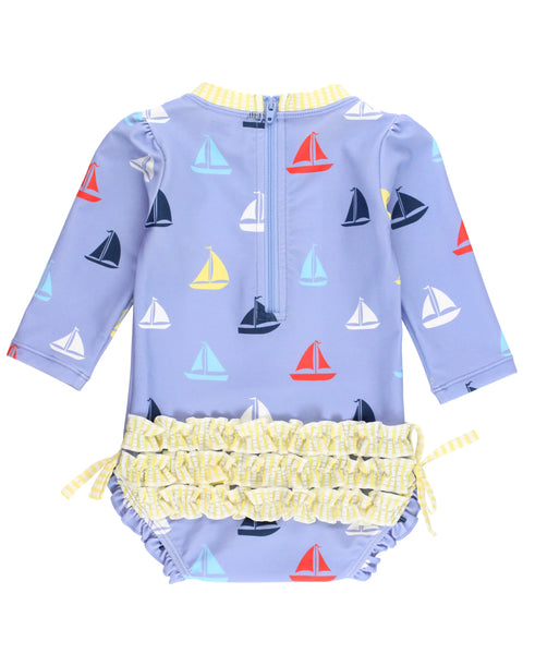 blue long sleeve rashguard suit with multi color sailboats all over and yellow seersucker trim and ruffles on bum