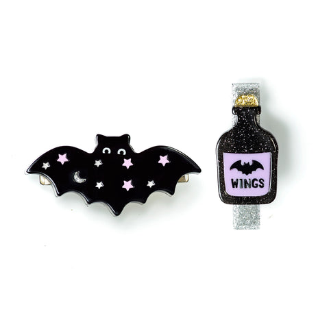 clip on the left is a black bat with purple stars and moon detail and the right is a magic potion that has a picture of a bat on it and says wings