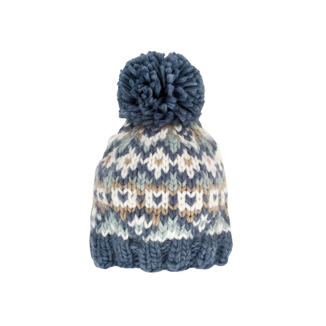 Knitted beanie with a patterned design and blue pom-pom on a white background