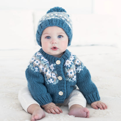 Baby wearing a blue knitted sweater and hat on a white background