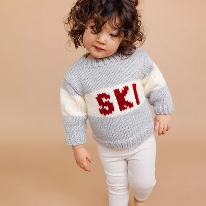Child wearing a knitted sweater with &