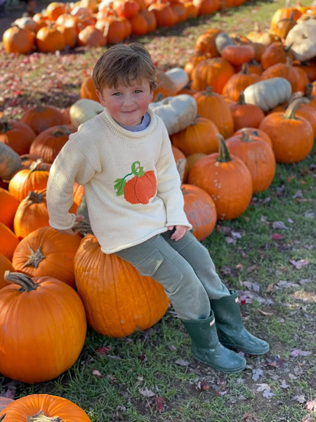 ivory long sleeve sweater with orange pumpkin - wearing in a pumpkin patch