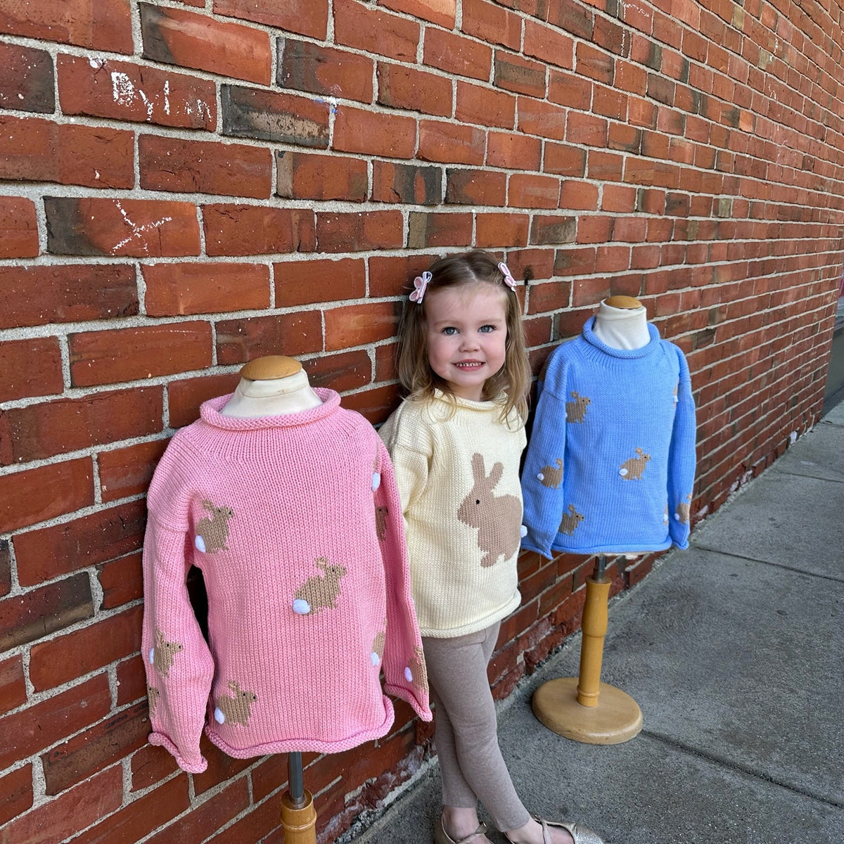 girl wearing bunny sweater standing with two bunny sweaters