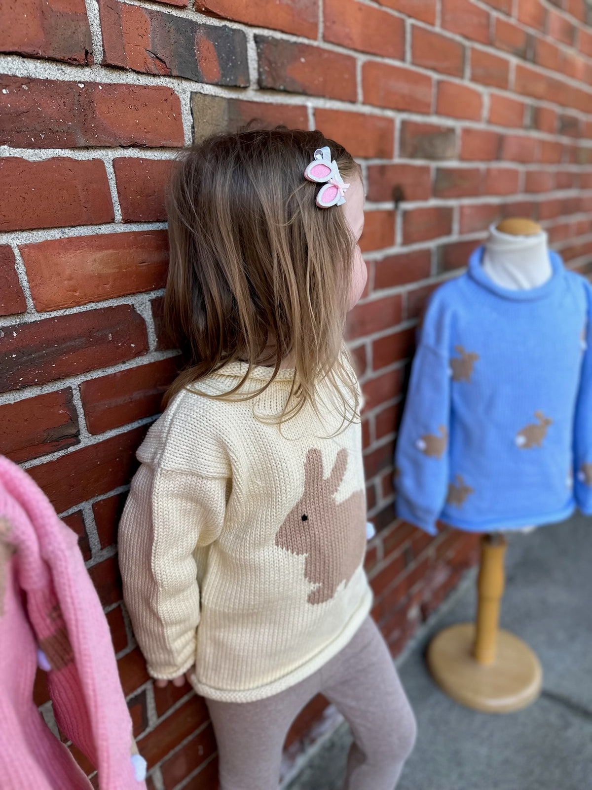 girl wearing bunny sweater standing with two bunny sweaters