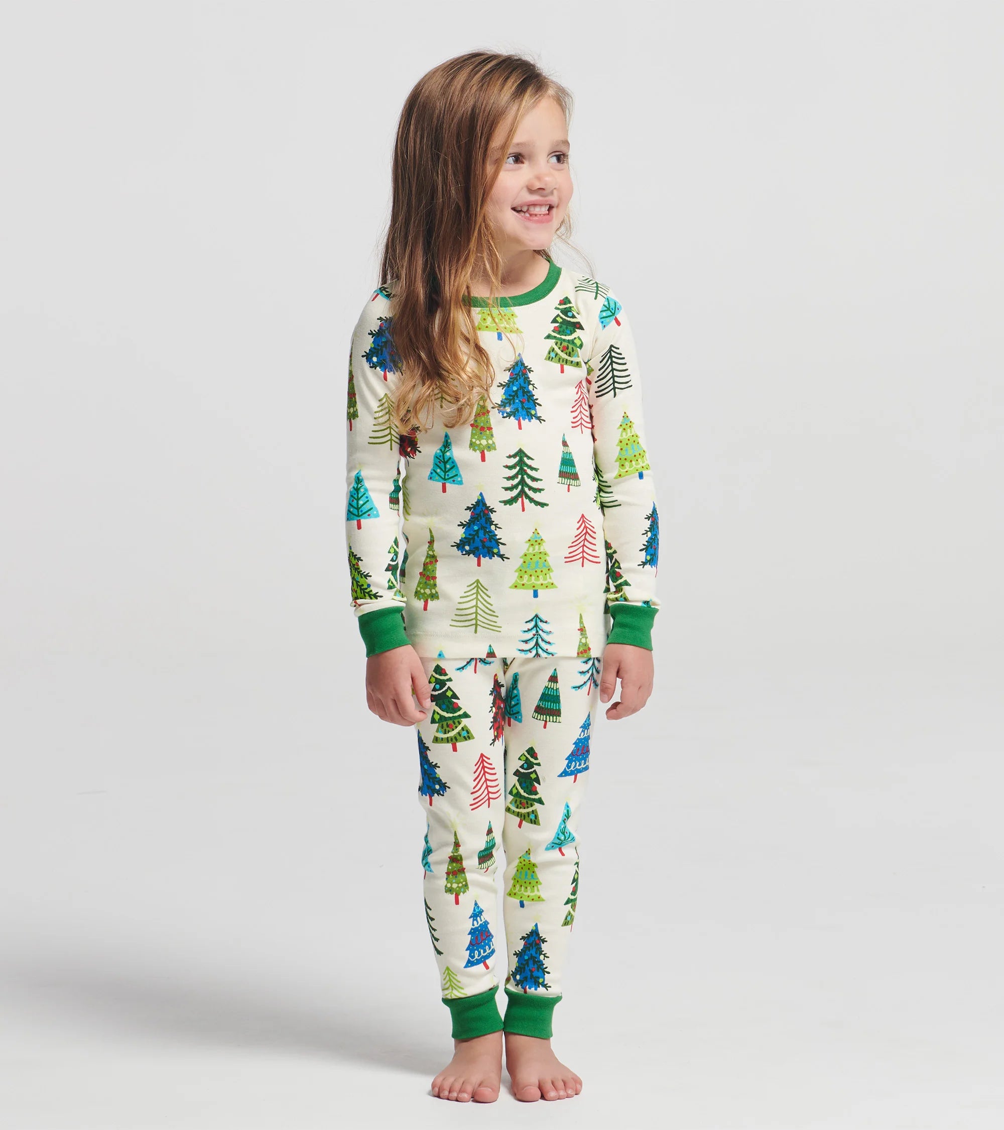 Child wearing a Christmas tree patterned onesie on a plain background