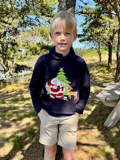 Child wearing a navy blue sweater with a Christmas design outdoors