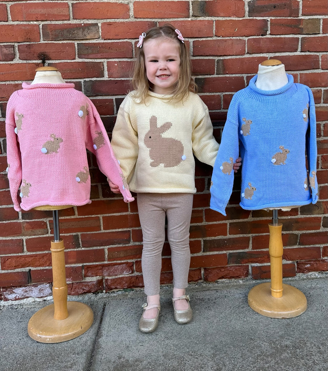 girl wearing bunny sweater standing with two bunny sweaters