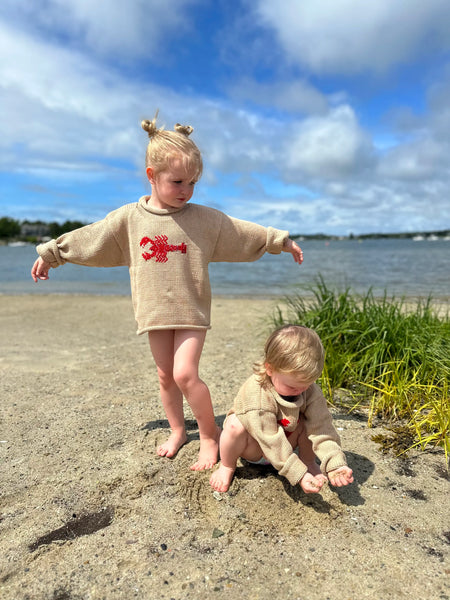 blonde girl wearing tan lobster sweater standing next to baby sister