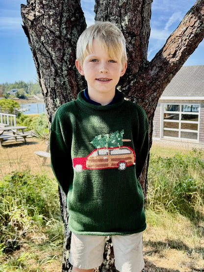 green sweater with red car carrying Christmas tree