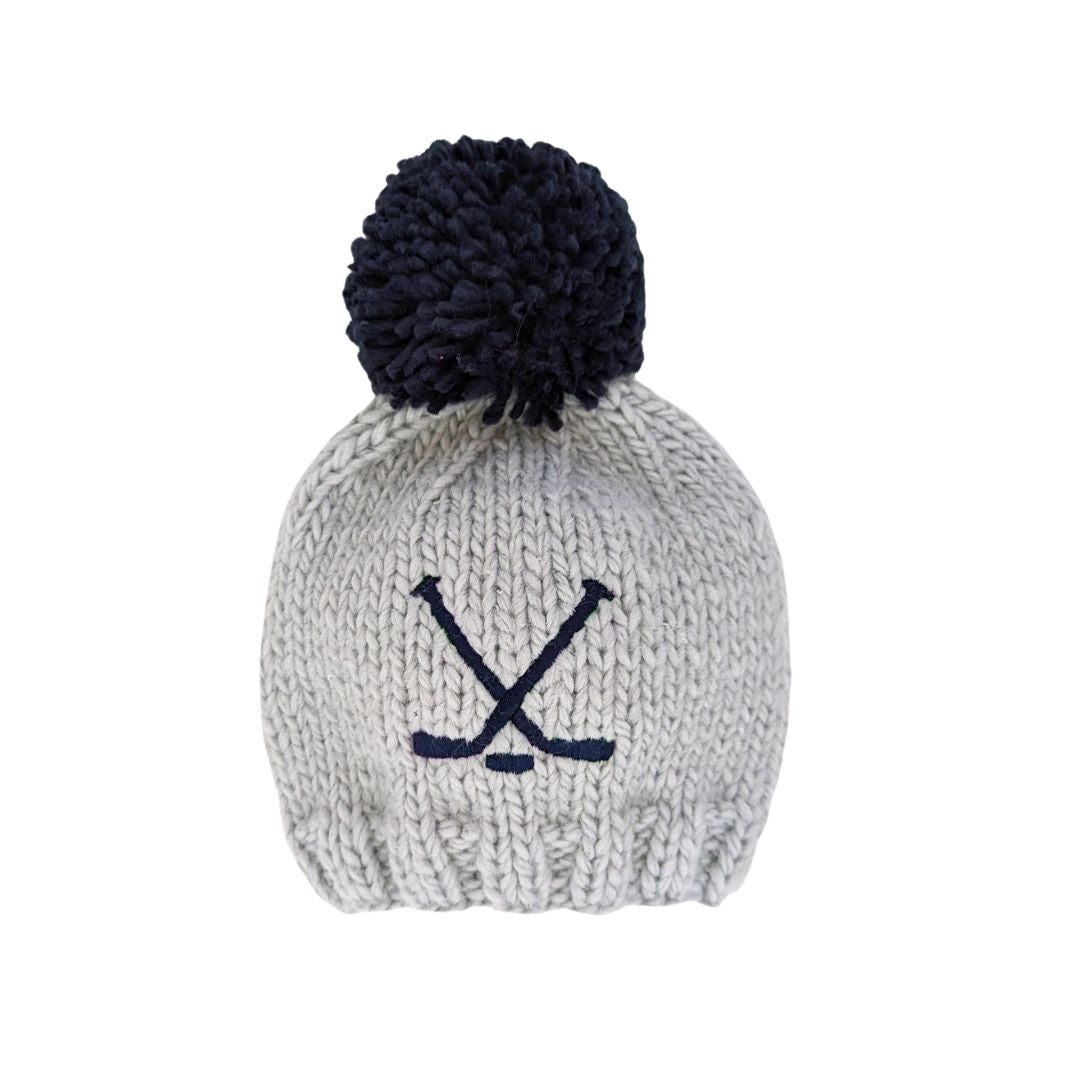 Knitted beanie with navy pom-pom and crossbones on a white background