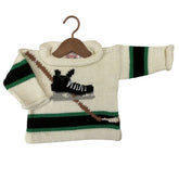 A knit baby sweater on a wooden hanger, featuring a cream base with green and black horizontal stripes, a brown hockey stick graphic, and a black-and-white hockey player motif on the chest.