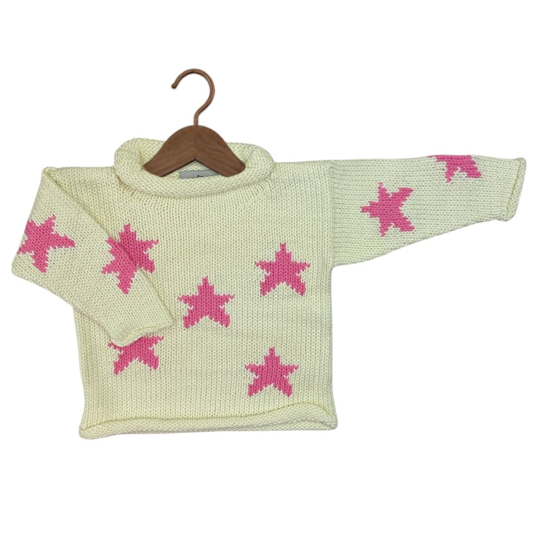A cream-colored knit sweater with pink star patterns, displayed on a wooden hanger against a plain white background.