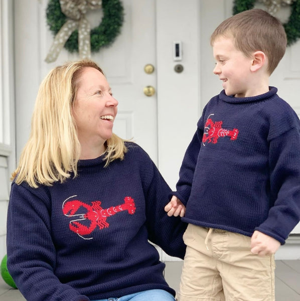 mom wearing navy lobster sweater and son is wearing kids version of sweater