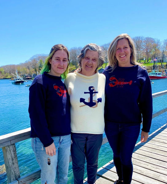 two ladies wearing navy lobster sweater and middle woman is wearing ivory anchor rope sweater
