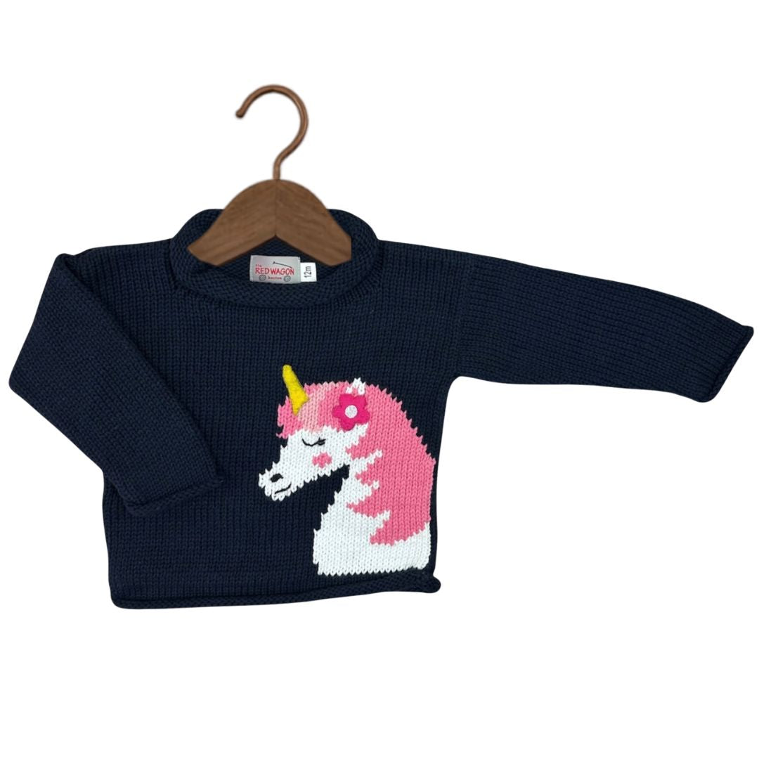 A navy blue ribbed knit baby sweater with a knitted unicorn design on the front, featuring a pink and white body with a yellow horn, displayed on a wooden hanger against a white background.