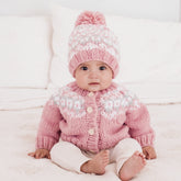 Baby wearing a pink knitted sweater and hat on a white background