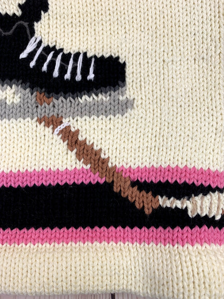 ivory long sleeve sweater with hockey skate and stick with pink and black stripe on waist and each sleeve