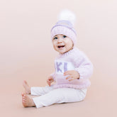 Baby wearing a pink knit sweater and hat with &