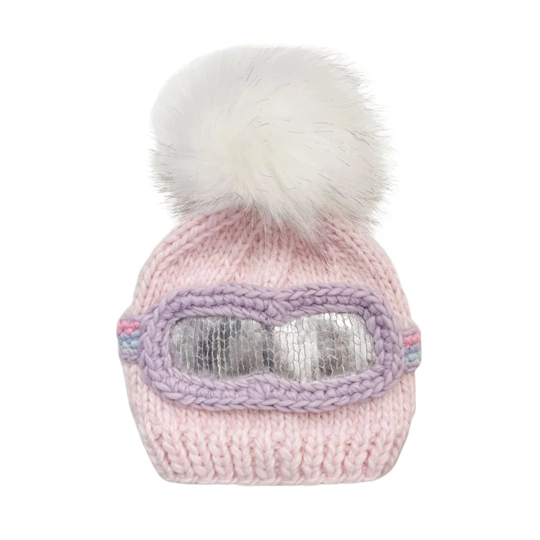 Pink knitted hat with goggles and white pom-pom on a white background