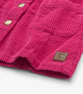 Close-up of a bright pink corduroy jacket or cardigan with metal snap buttons and a small brown leather patch on the front, photographed on a light gray background.