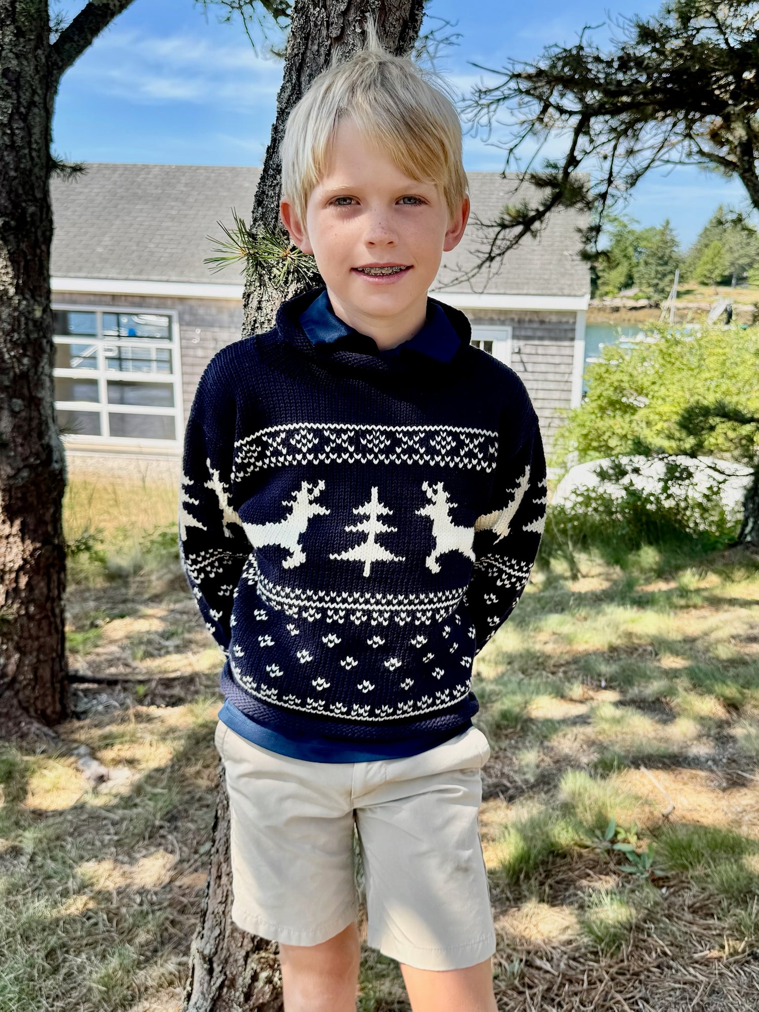 Child wearing a navy blue sweater with white patterns outdoors