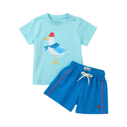 set featuring light blue top with seagull wearing red beanie and scarf, with matching solid blue shorts with red stripe on each side
