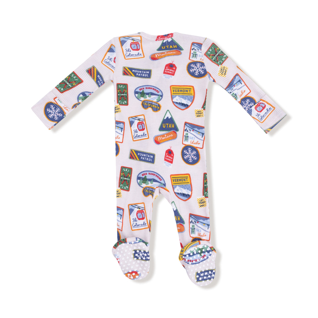 Baby onesie with travel-themed patches on a white background