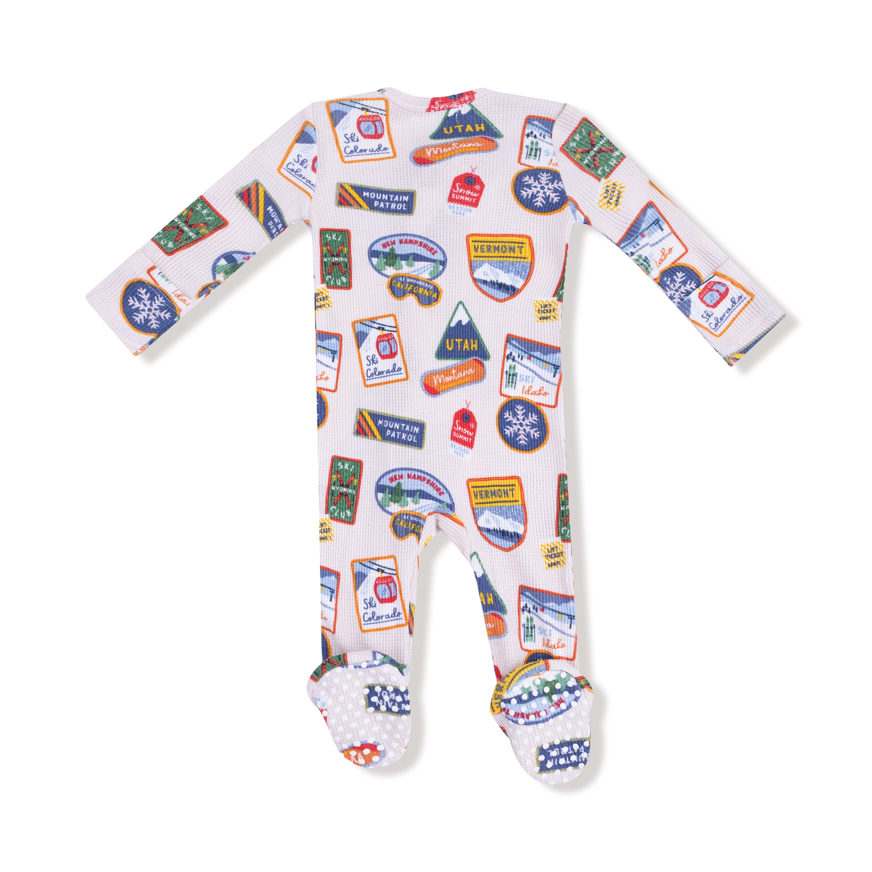 Baby onesie with travel-themed patches on a white background