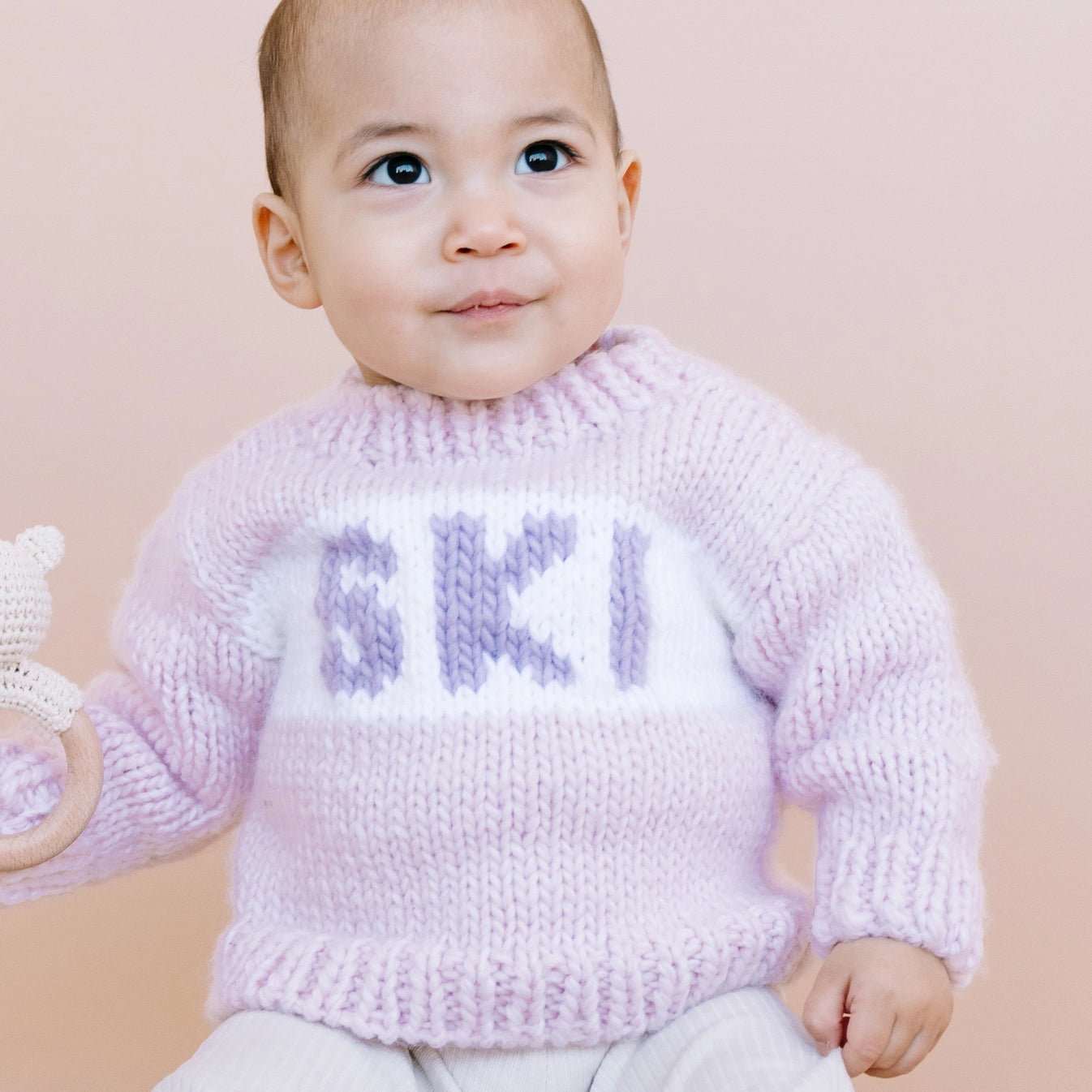 Baby wearing a pink knitted sweater with &